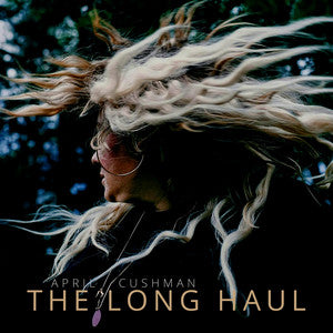 Person with long, flowing hair against a dark background with 'April Cushman' and 'The Long Haul' text.